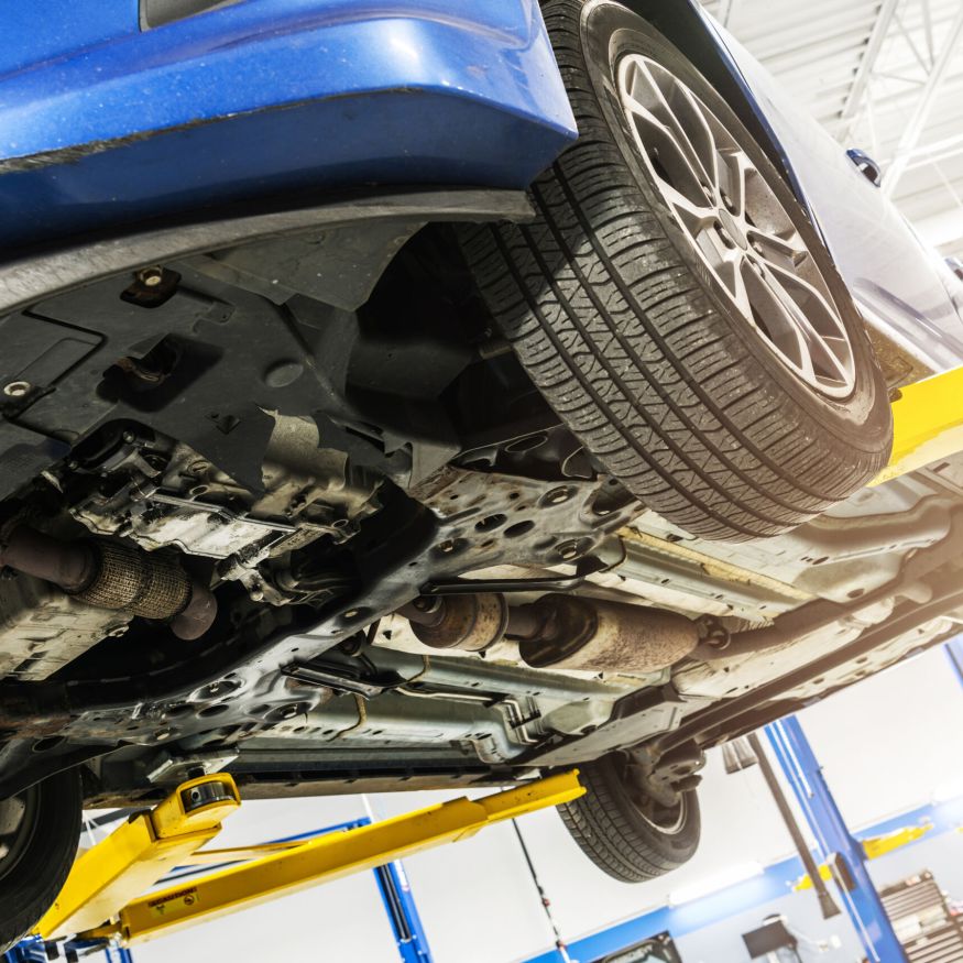 Modern Car Under Scheduled Maintenance Inside Auto Service. Vehicle Up on a Lift. Automotive Industry Theme.